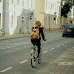 woman in black jacket riding bicycle on road during daytime